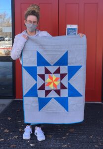 Jill Smith from Ronald McDonald Charities Idaho holding quilt with a large star