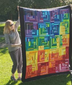 woman holding up a colorful quilt