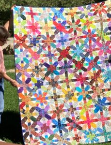 woman holding up bright color quilt