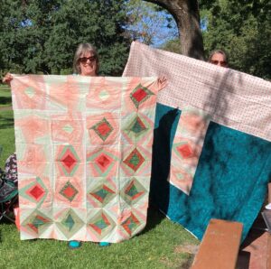 women holding up quilts